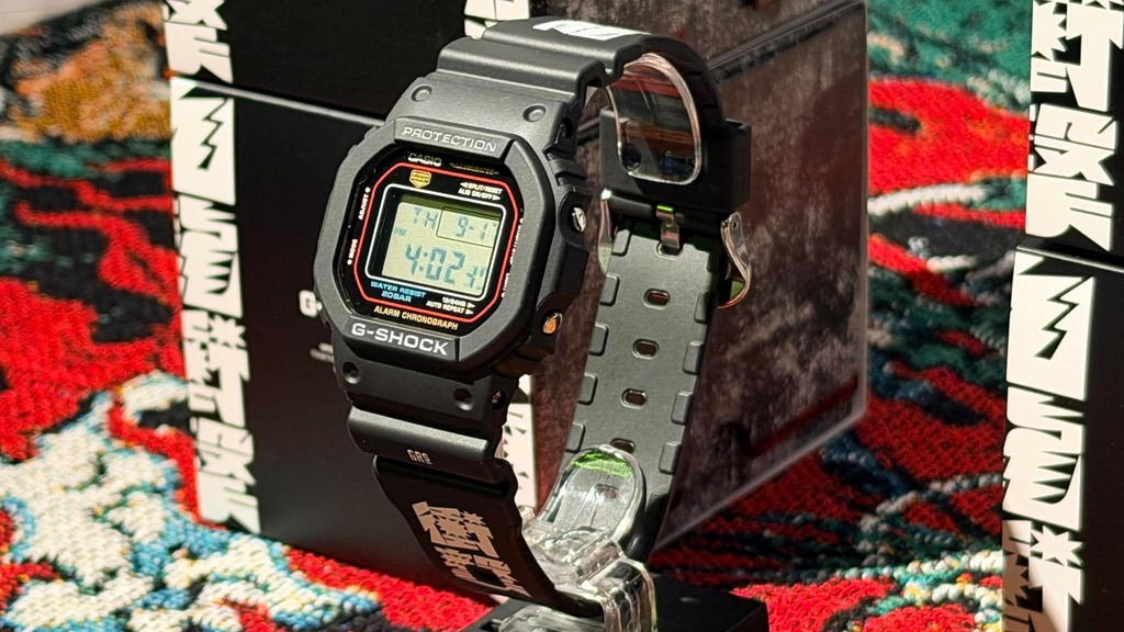 「九龍衝擊」是以 Casio 經典的 5600 方型錶身為藍本，錶帶印有搶眼的「九龍衝擊」及 GRS 品牌字樣。